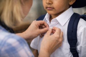 Parent helping child button school uniform